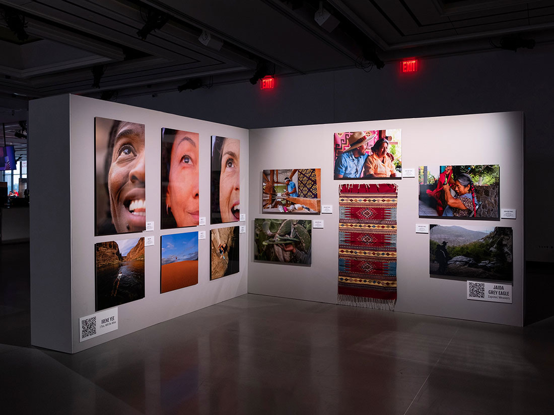 A dark gallery at a FUJIKINA festival, with walls of portrait and landscape prints