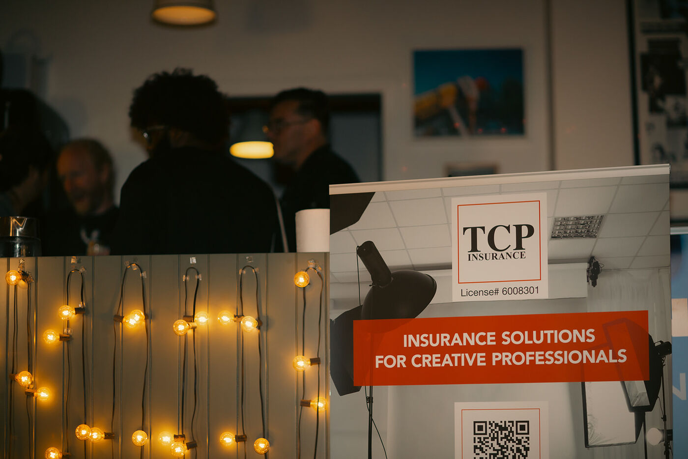 A TCP Insurance banner among the string lights